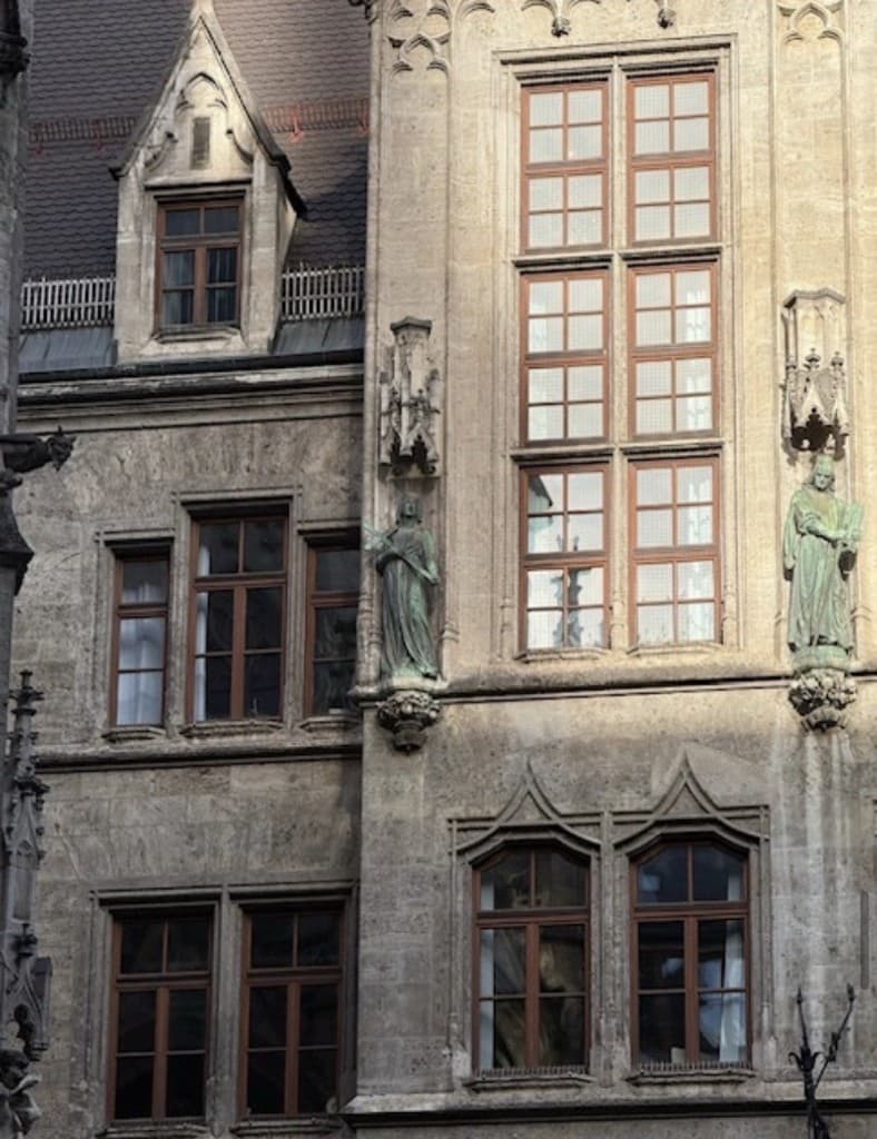 German Neo-Gothic stone facade with mullioned windows and verdigris statues