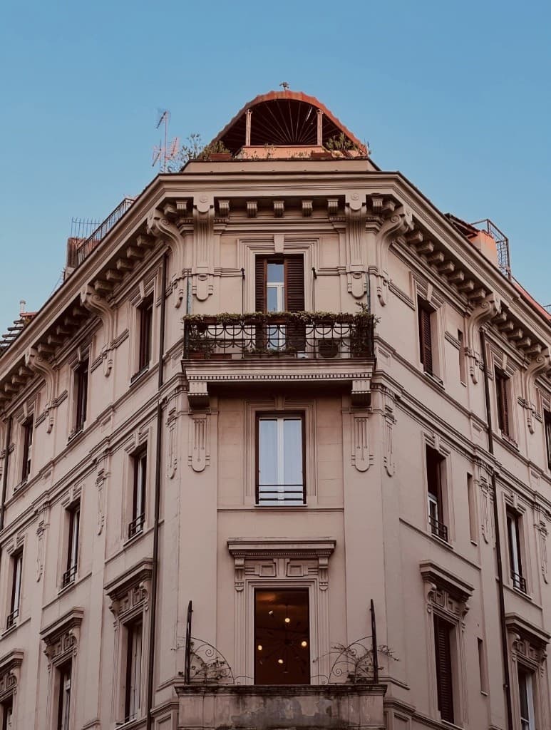 Italian corner building with wrought-iron balconies and cornice