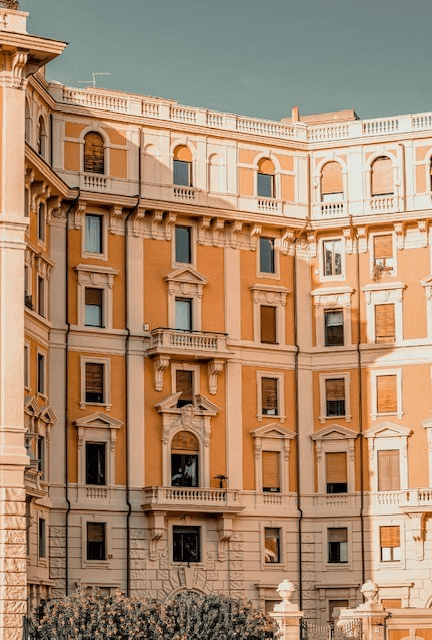 Italian ochre apartment facade with balconies and shutters